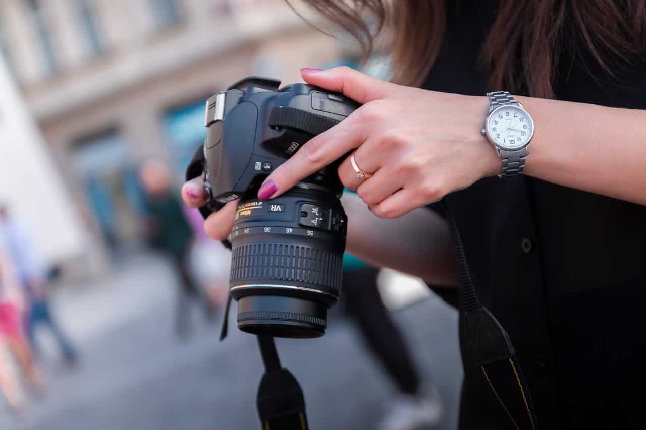 Close-up of a woman's hands adjusting a DSLR camera, capturing scenes