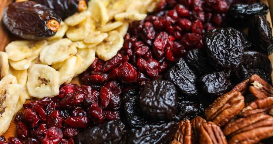 Assorted dried fruits and nuts, including dates, banana chips, dried cranberries, prunes, and pecans, rich in fiber and nutrients