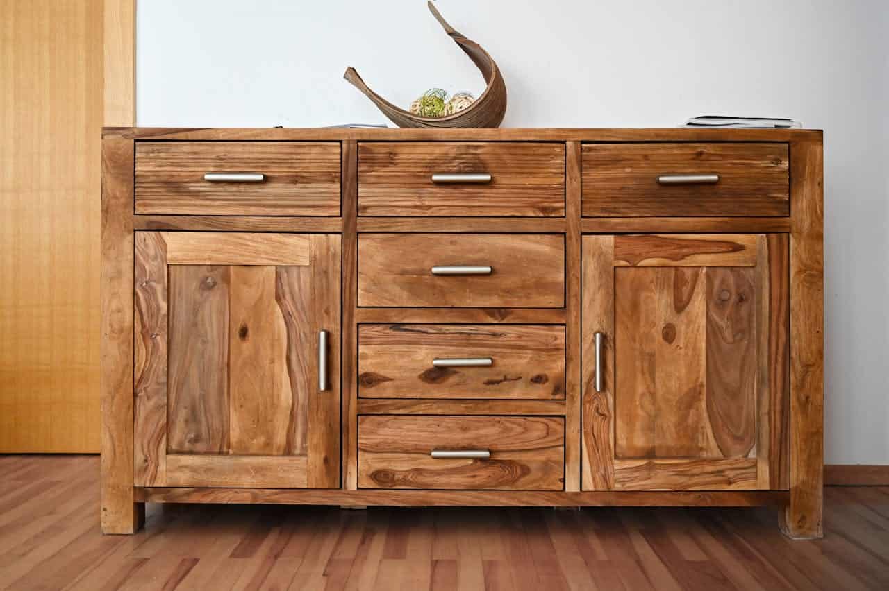 Wooden sideboard with six drawers and two cabinets featuring natural wood grain and metal handles on hardwood flooring