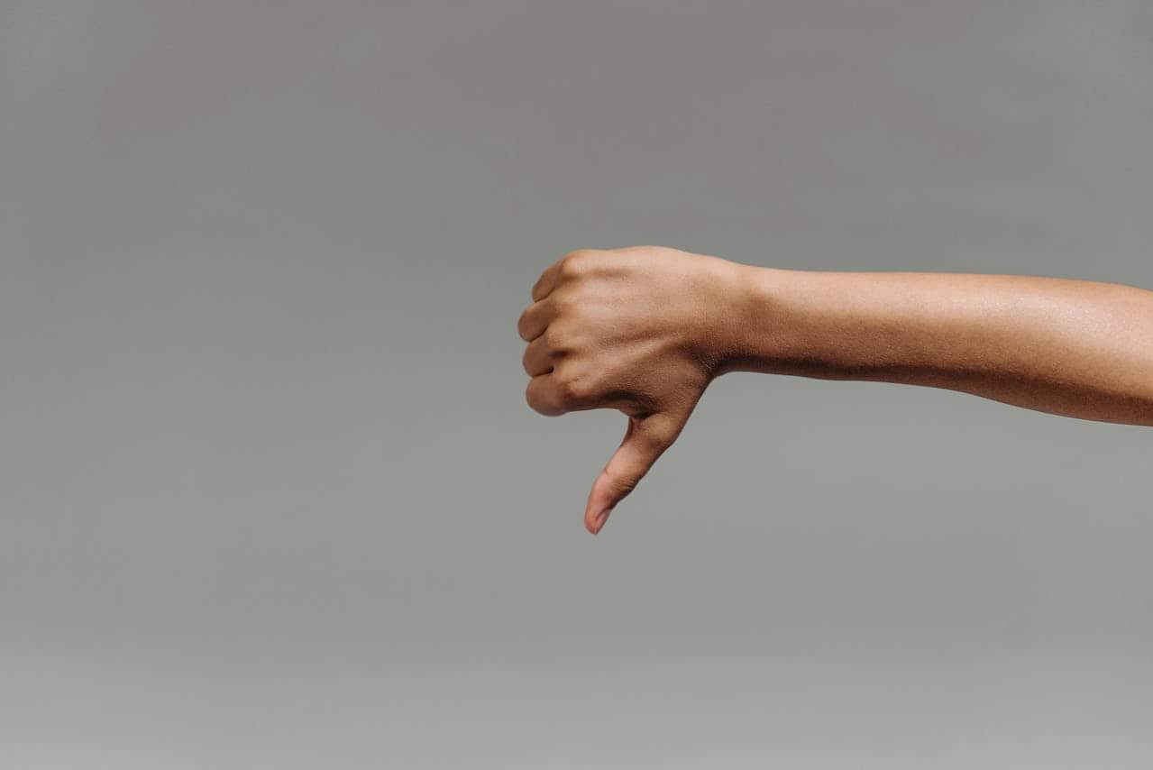 A hand making a thumbs-down gesture, negative expression, disapproval, isolated on a gray background