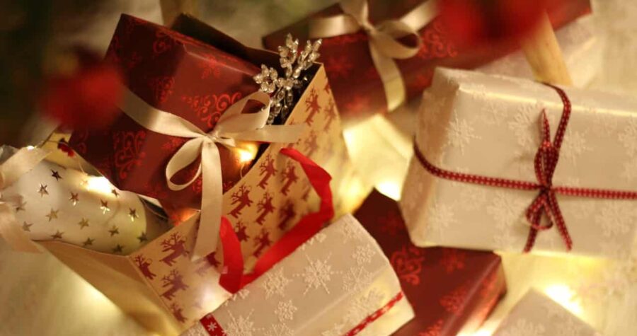 Christmas gifts wrapped in festive red and white paper, adorned with ribbons, snowflakes, and reindeer designs, placed together