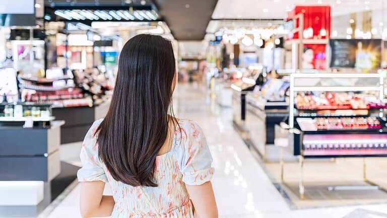 Woman standing in a shopping mall, facing the aisle, looking at retail displays, modern shopping experience