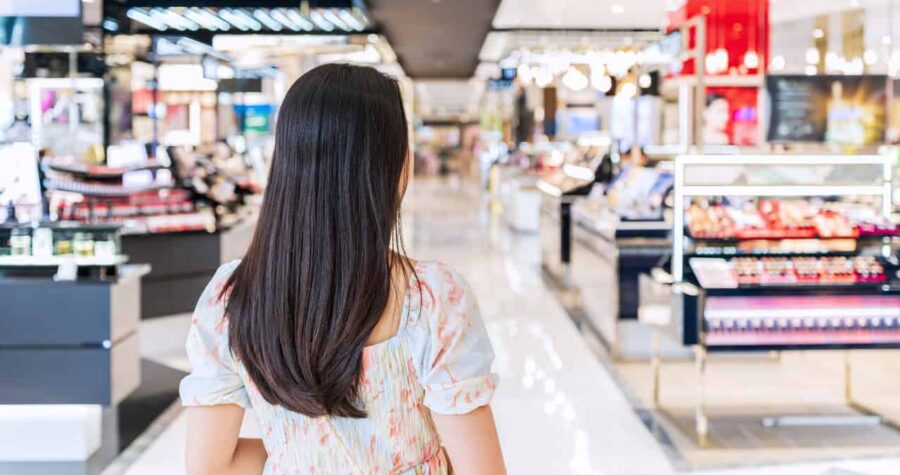 Woman standing in a shopping mall, facing the aisle, looking at retail displays, modern shopping experience