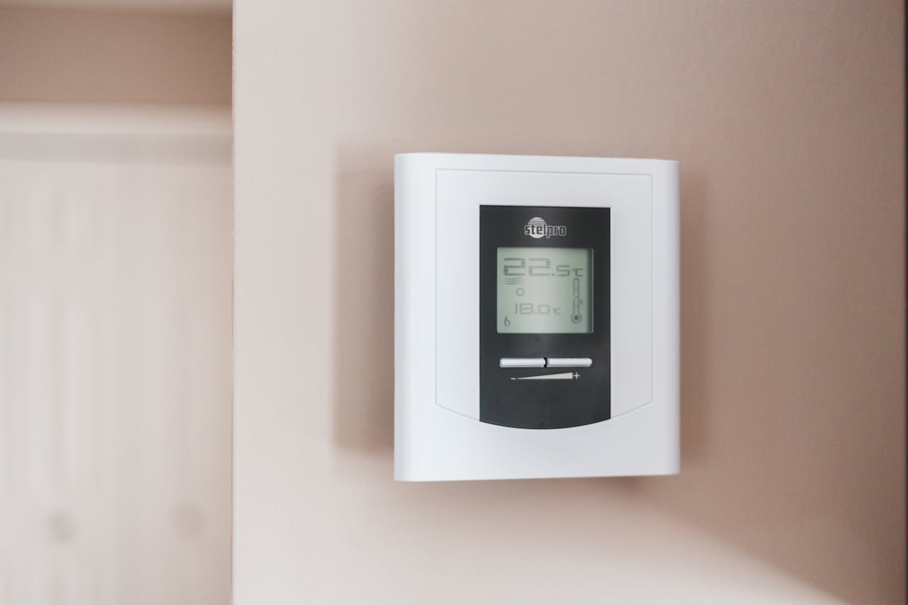 Digital thermostat mounted on wall, white housing with black display panel, showing temperature, "EVE Pro" brand logo visible at top of screen