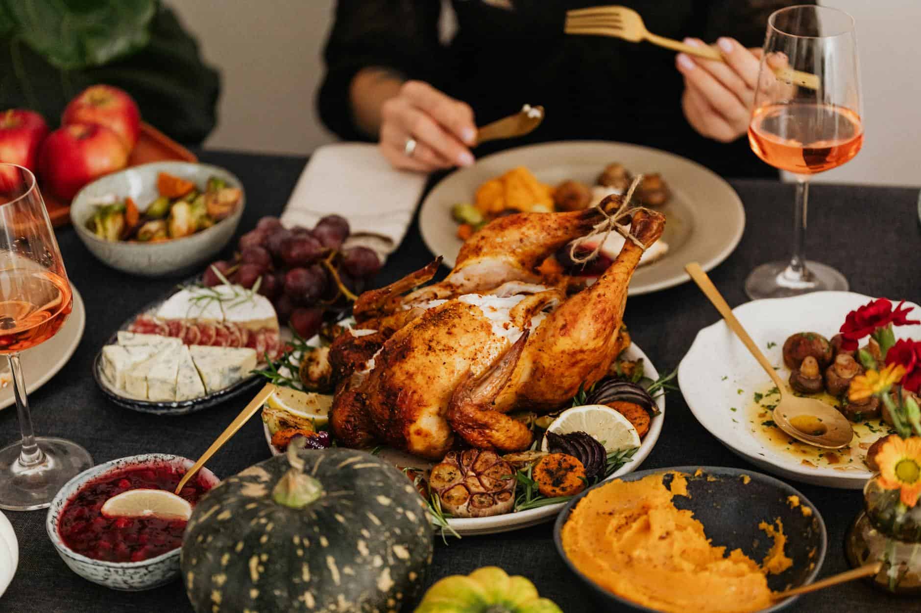 A festive Thanksgiving dinner spread featuring a golden roasted turkey, vegetables, and wine, perfect for holiday dining.