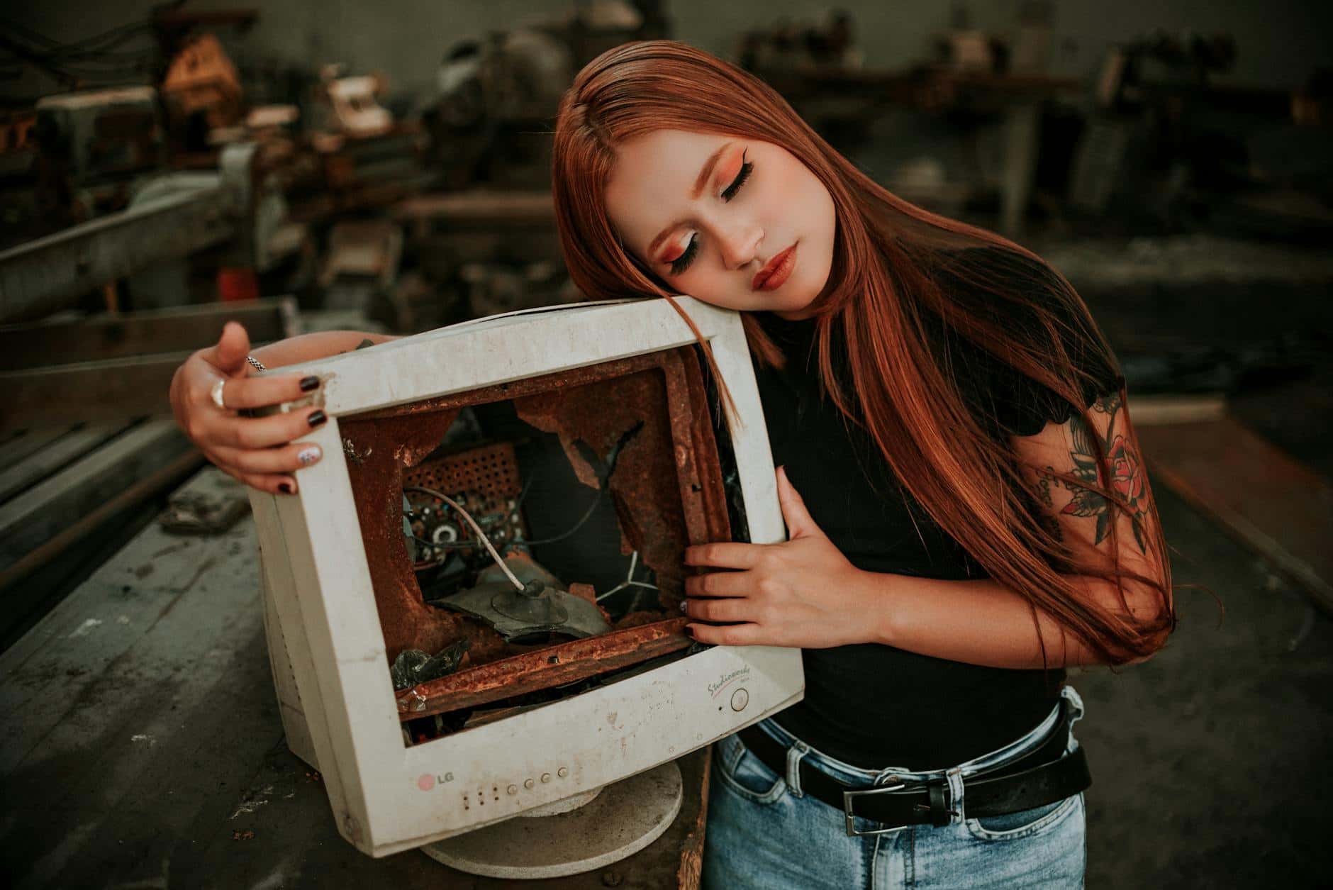 A woman embraces a vintage broken monitor, evoking nostalgia and style.
