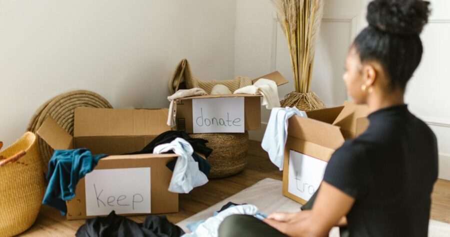A woman organizing clothes into labeled boxes for donation and keeping.