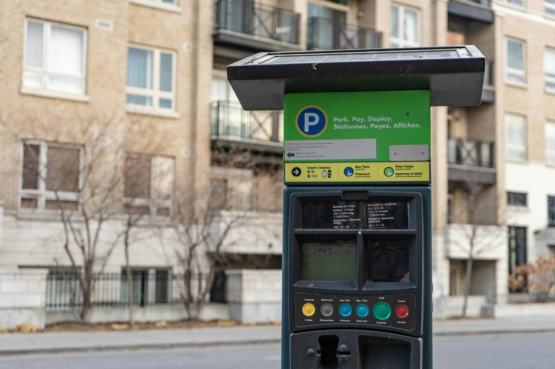 Close-up of a parking meter on an urban street with residential buildings in Ottawa, Canada.