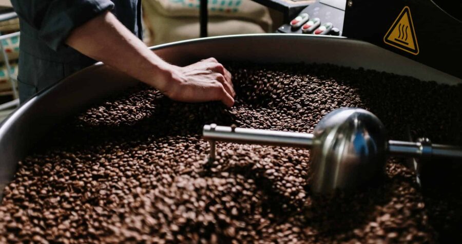 Close-up of a professional roasting coffee beans in an industrial setting, focusing on equipment and beans.