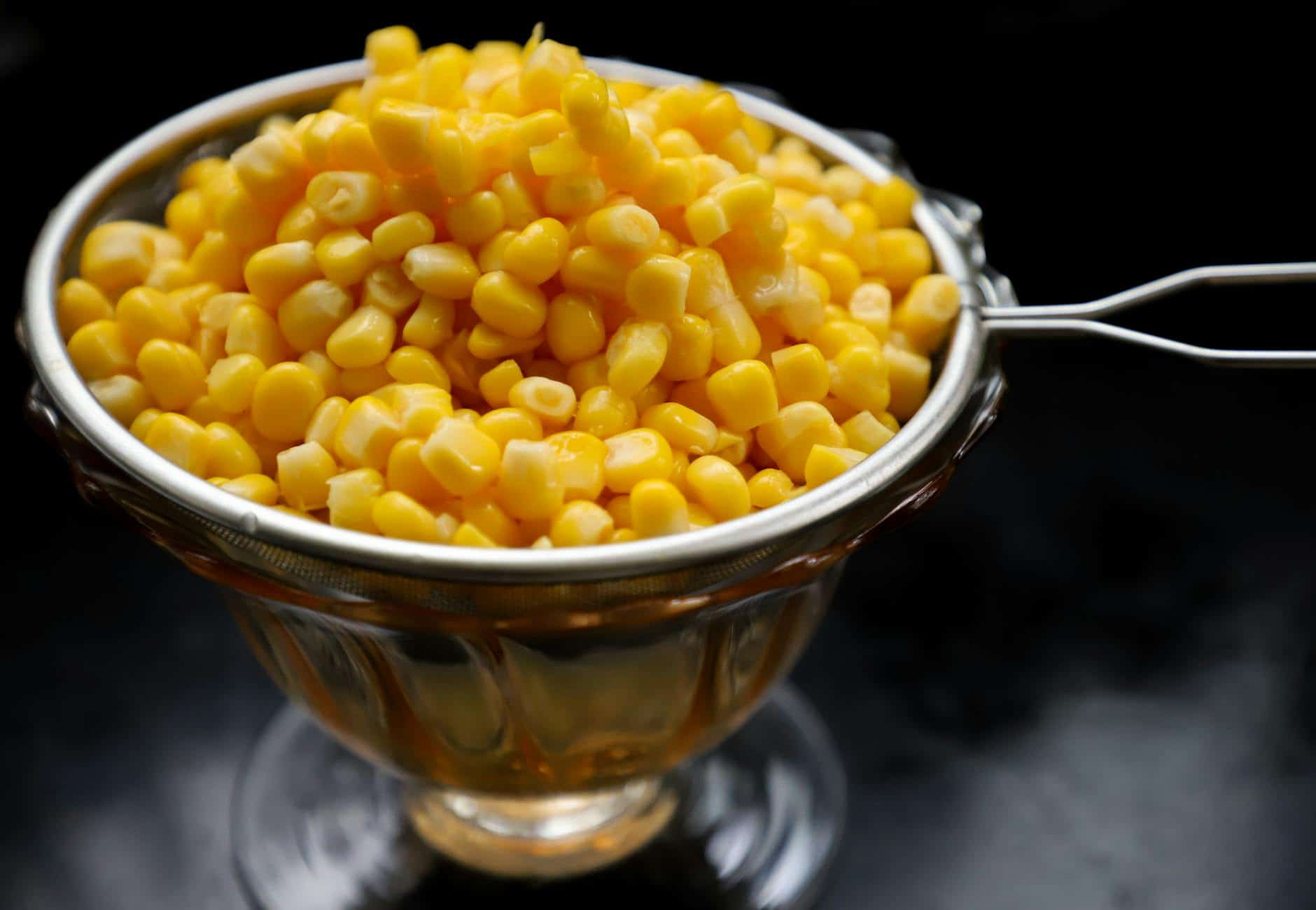 Close-up of fresh yellow corn kernels in a stainless steel bowl, perfect for food-related content.