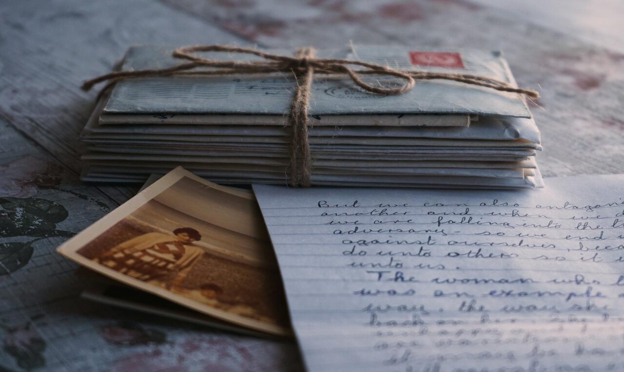 Close-up of vintage letters tied together with a twine, accompanied by an old photograph and handwritten note.