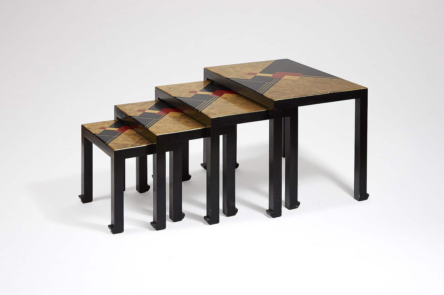 Set of four nesting tables with black metal frames, gold tops featuring geometric red and black artistic design, arranged in descending size order against white background