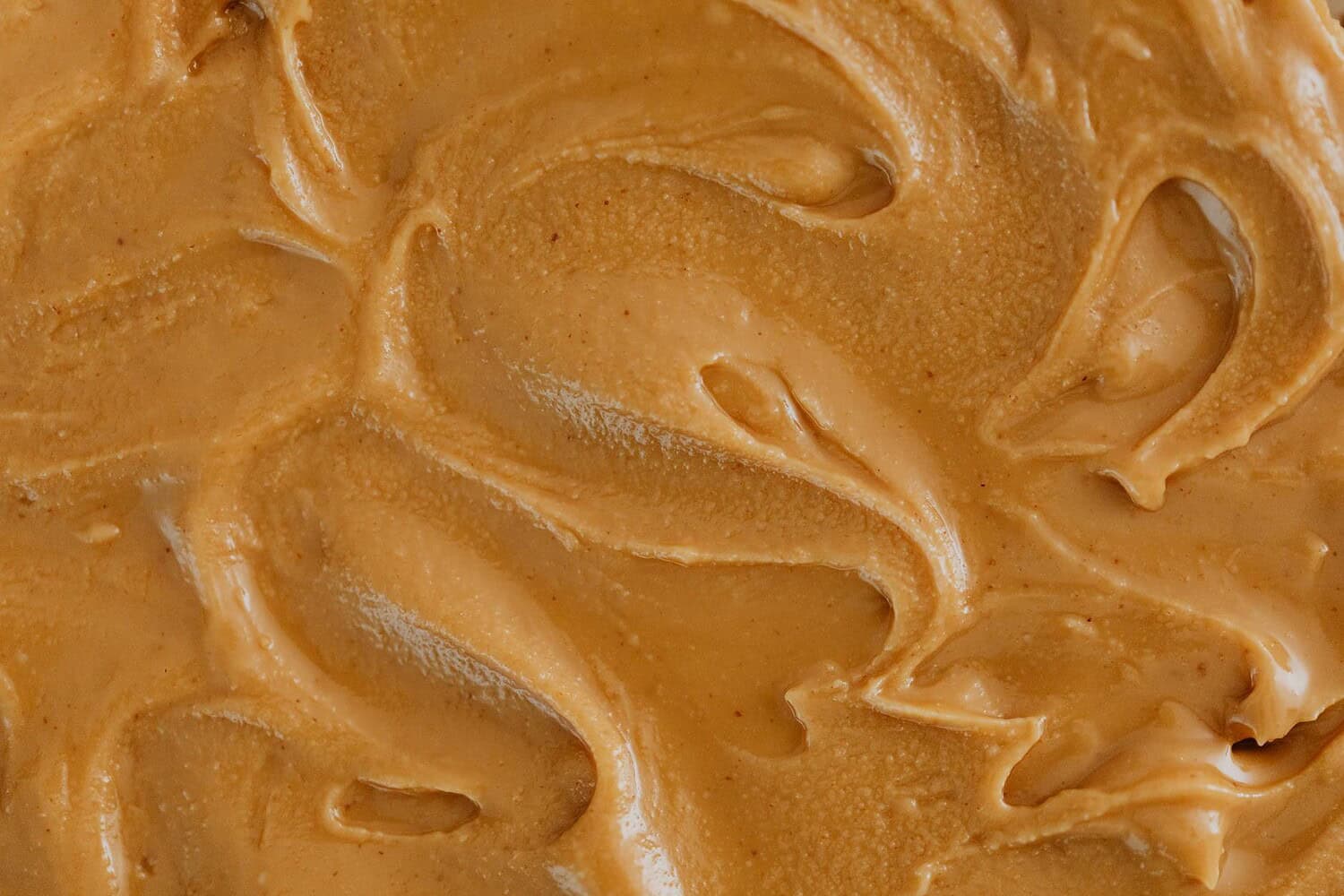 Smooth and creamy peanut butter texture with swirls, perfect for food and culinary themes