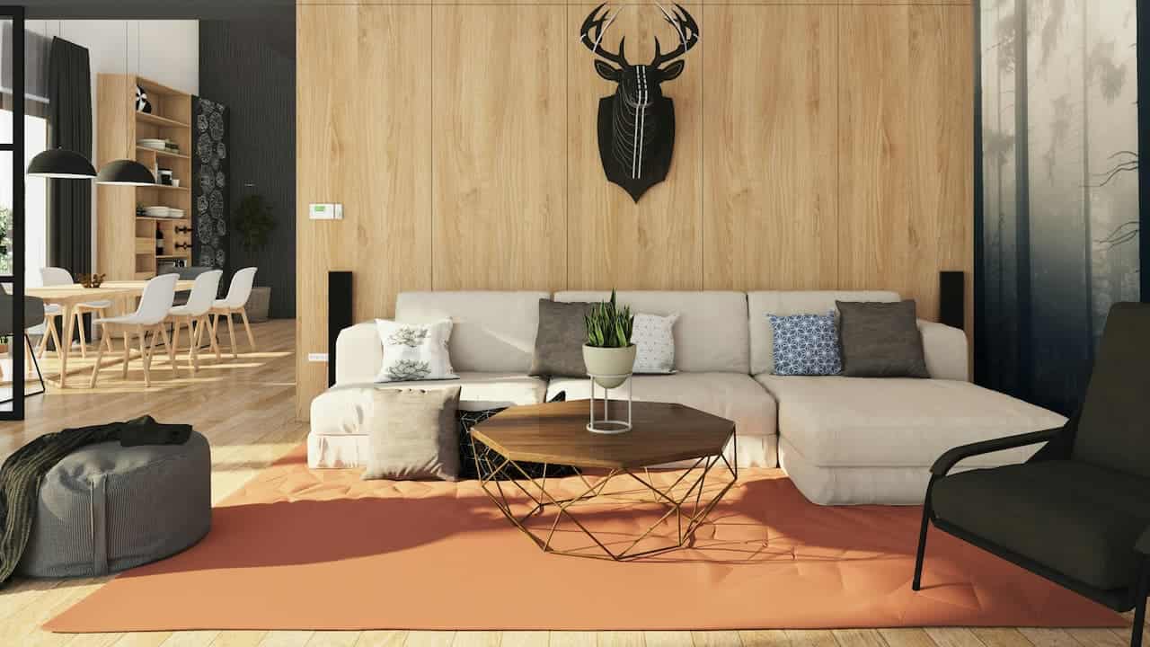 Modern living room with light wood paneling, cream sectional sofa, geometric coffee table, deer head decoration, and dining area beyond