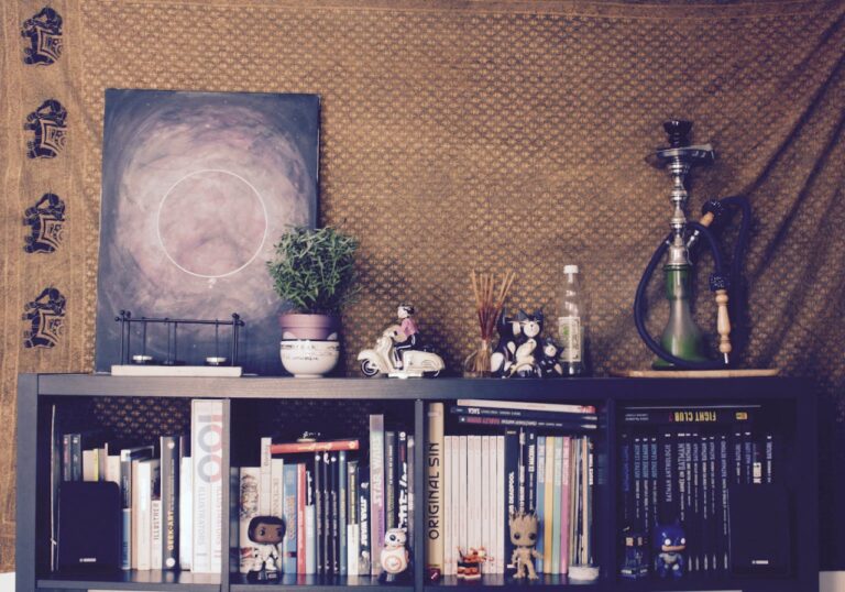 A cozy shelf with books, figurines, a plant, incense sticks, a hookah, and a painting, the background features a patterned cloth, a decorative scene with pop culture references, vibrant and personal display with pop culture items like Star Wars and Marvel comics, creating a casual and creative atmosphere