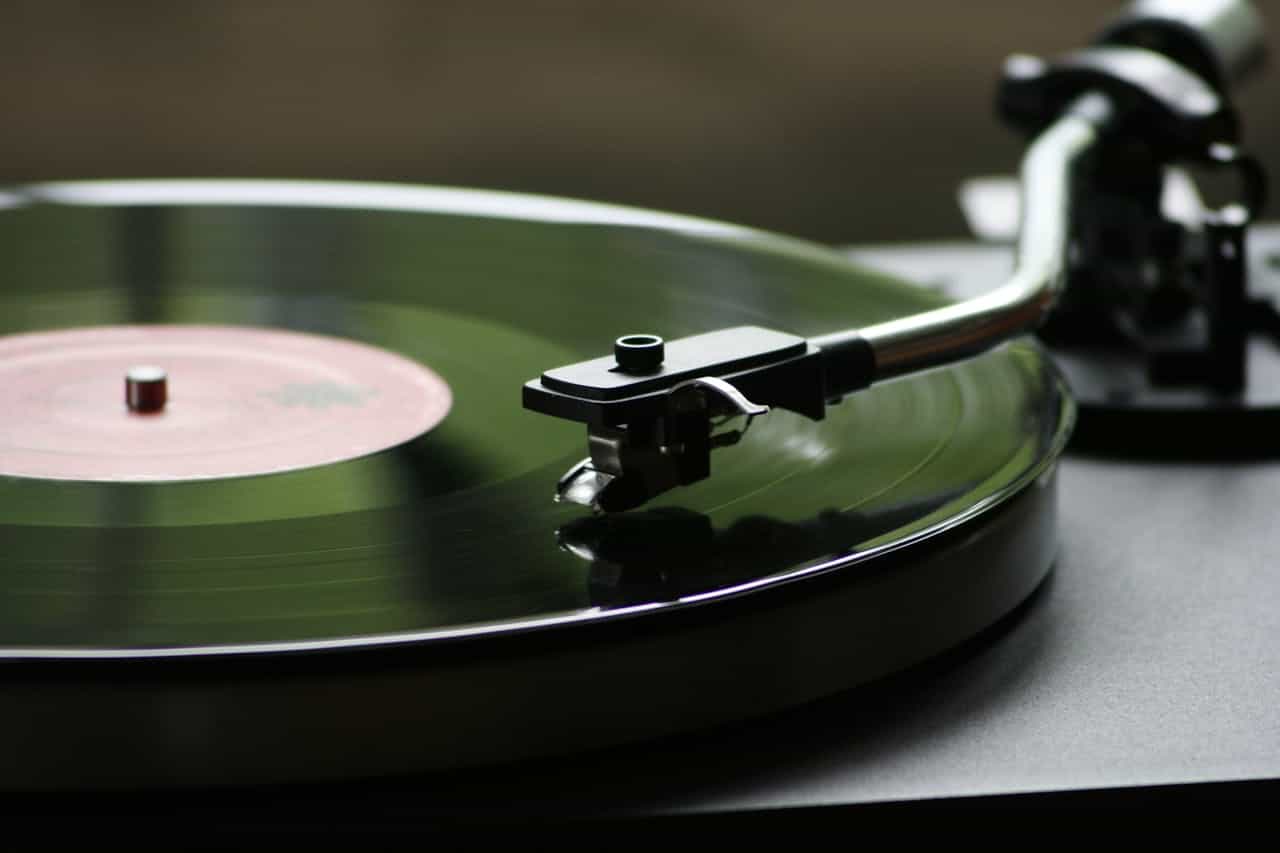 Close-up of a turntable playing a vinyl record, with the needle arm positioned on the grooves of the record, reflecting the smooth, spinning motion of the record's surface