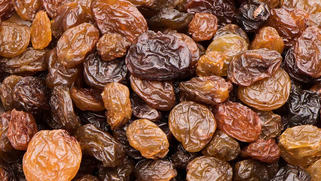 Close-up view of numerous dried raisins showing wrinkled brown surfaces and varying sizes scattered densely across the frame