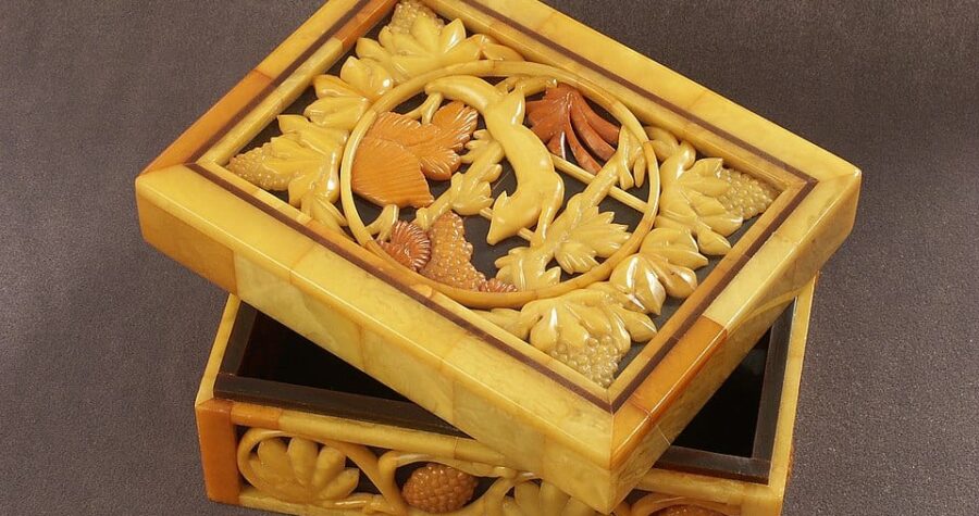 Wooden decorative box, partially open lid, intricate floral and bird design on top, rich yellow and brown tones, placed on a brown surface