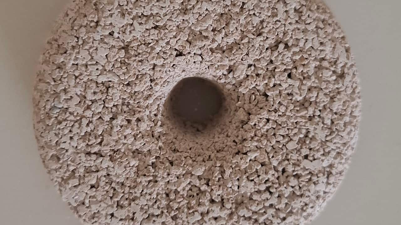 Round, beige mosquito dunk with rough, grainy texture, donut-shaped with a central hole