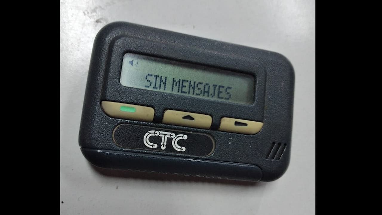 Black CTC-branded pager with a monochrome screen displaying the message “SIN MENSAJES,” resting on a white surface, with three beige navigation buttons below the screen
