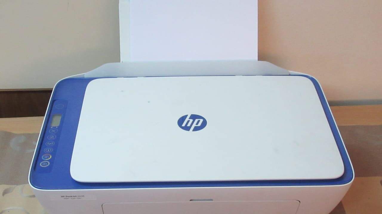 HP DeskJet all-in-one printer with a paper tray loaded and ready, sitting on a wooden surface