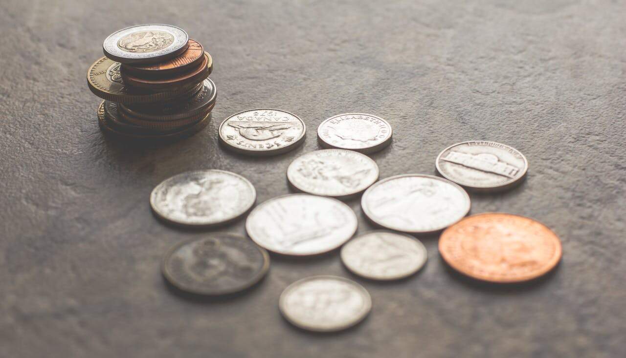 Assorted loose coins scattered and stacked on a textured surface, including Canadian and U.S. currency