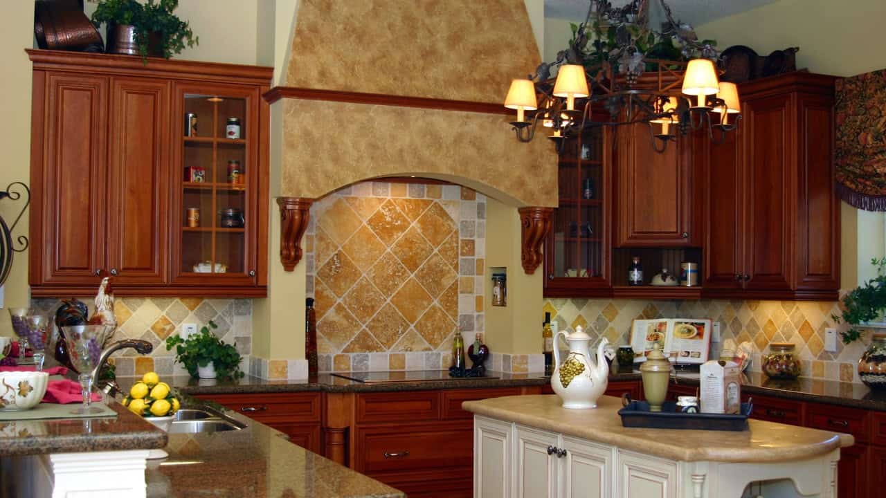 Tuscan kitchen, wood cabinets, tiled backsplash, ornate hood, marble countertop, chandelier lighting
