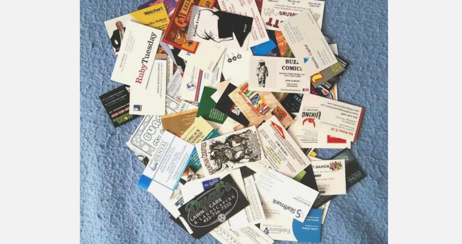 A large pile of assorted business cards scattered on a blue fabric surface