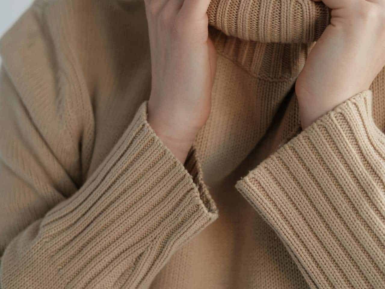 Light brown cashmere sweater neatly folded, soft texture visible, warm and cozy fabric