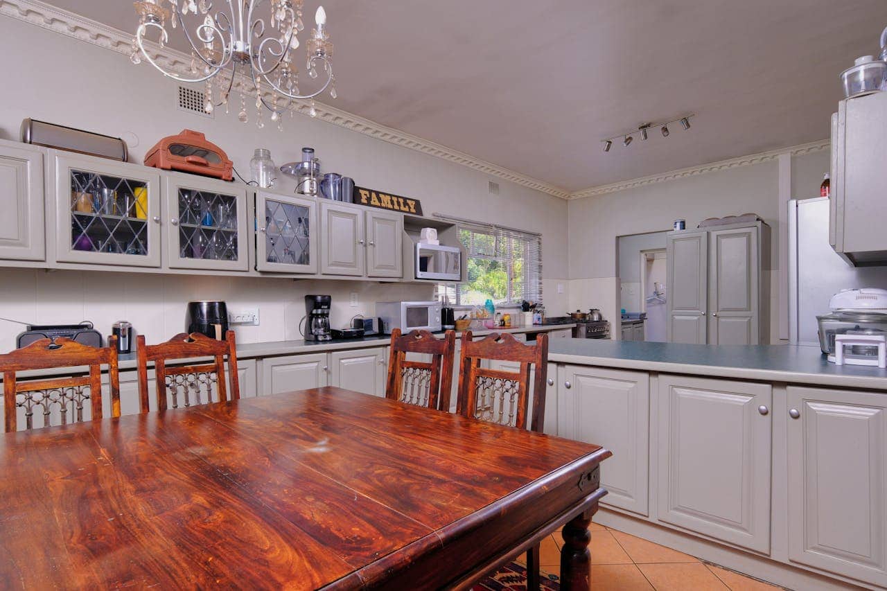 Kitchen with white cabinets, wooden dining table, crystal chandelier, coffee maker, microwave, and "FAMILY" sign on display shelf