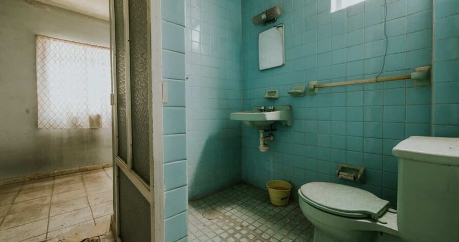 Retro Colorful Toilet and Sink with turquoise tile walls, white toilet, small sink, and adjoining room visible through doorway with textured glass