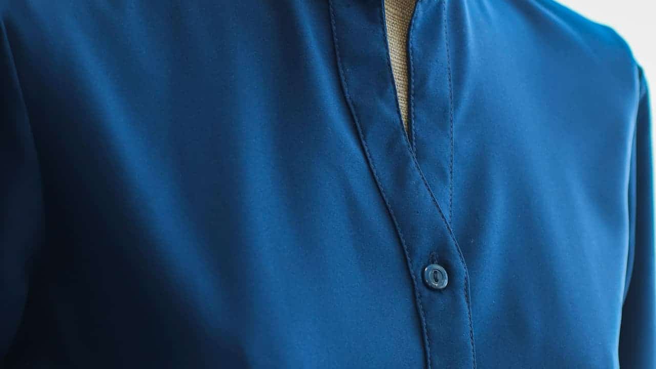 Classic blue chambray shirt with button-down collar, neatly folded, light denim-like fabric texture