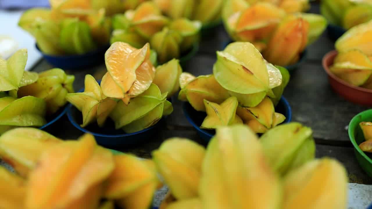 Close-up of ripe star fruits (carambola) displayed in plastic bowls at a market