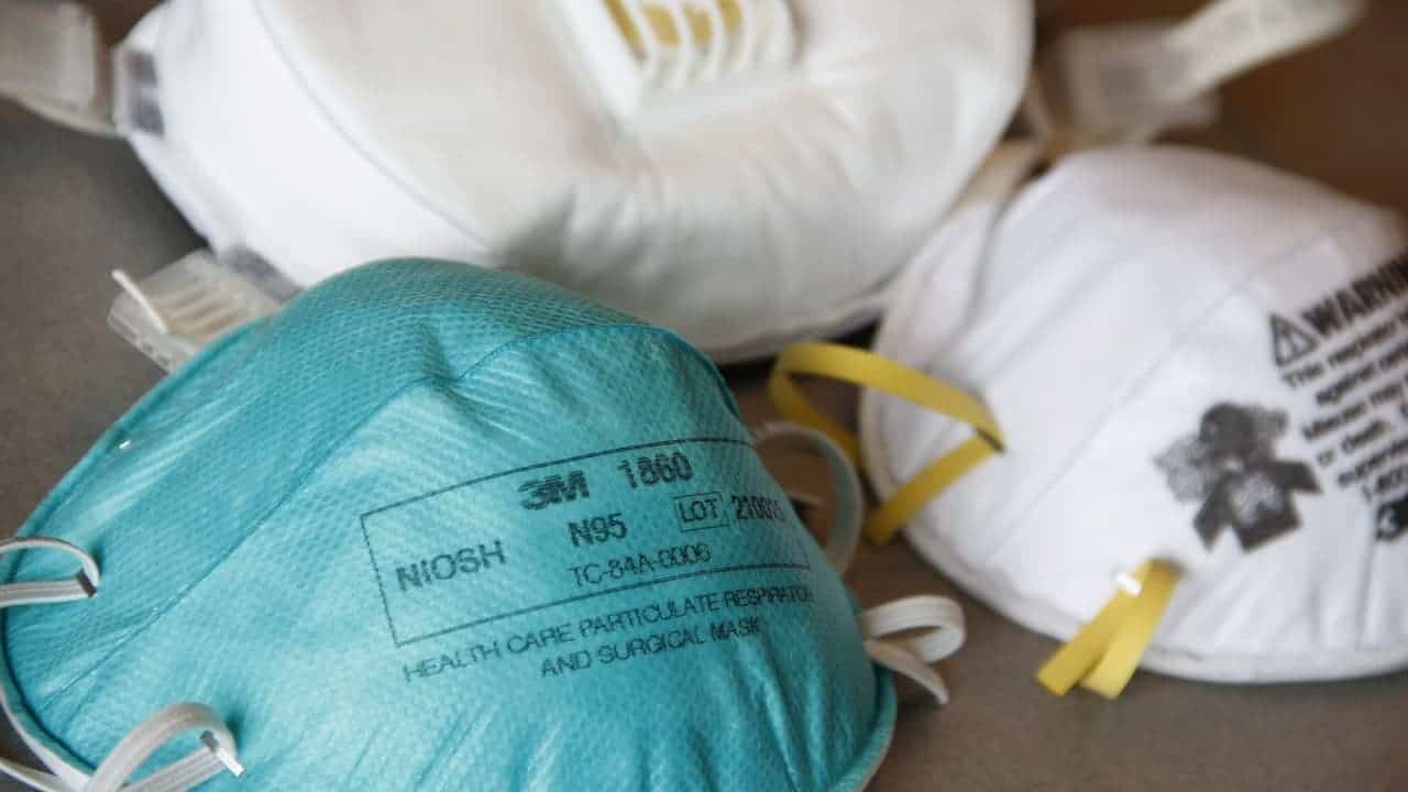 Blue 3M N95 respirator mask with yellow straps alongside white N95 masks, NIOSH approved healthcare particulate respirators