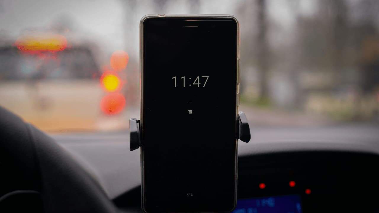 Smartphone secured in a dashboard-mounted phone holder inside a car