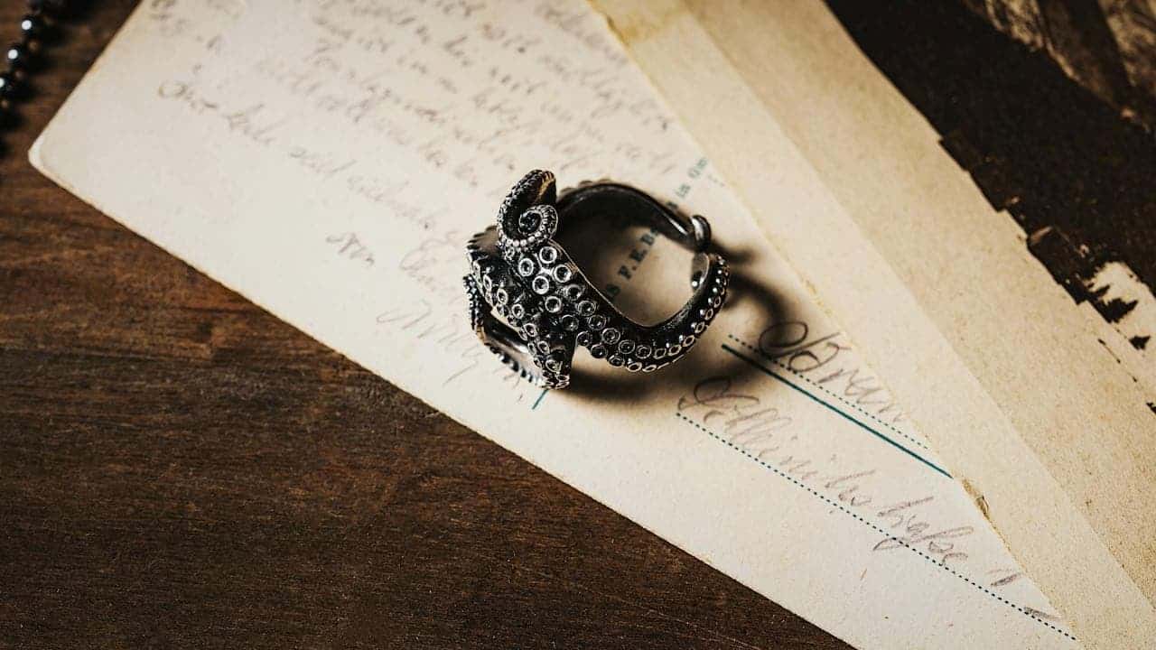 Vintage ornate silver ring with detailed metalwork placed on aged handwritten letters and documents on wooden surface