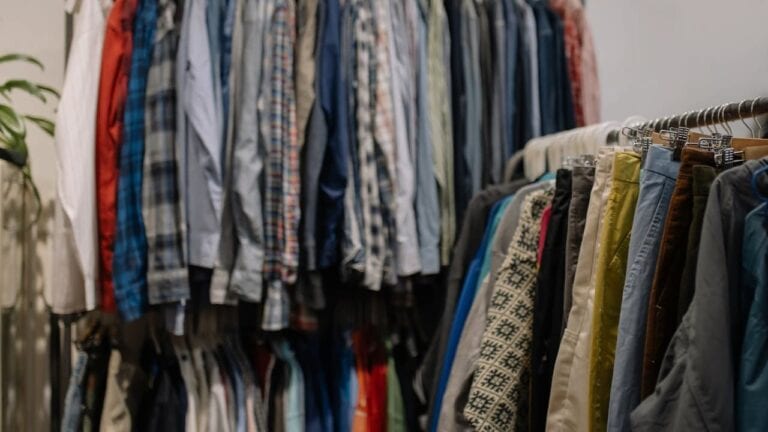 Organized closet with formal shirts and pants on hangers, featuring plaid patterns, solid colors, and business attire arrangements