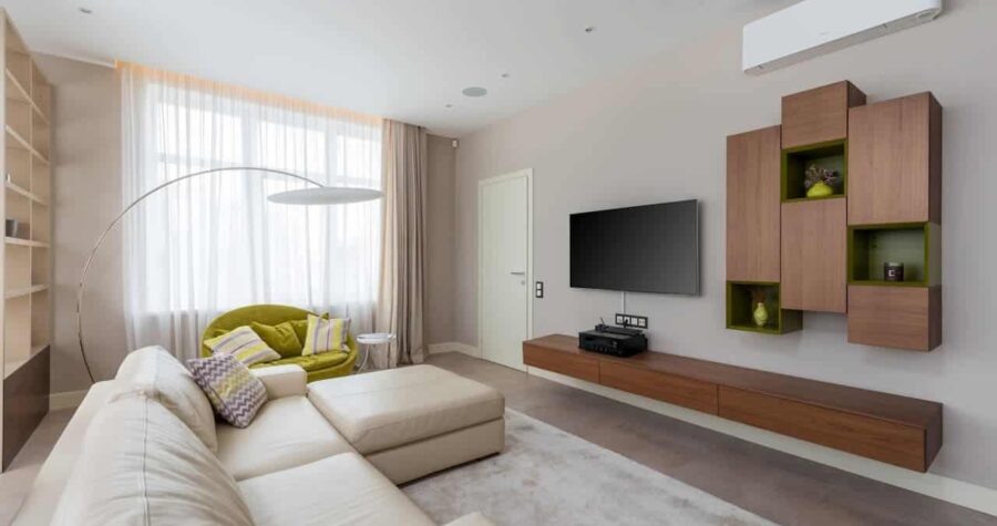 Modern living room with white modular sofa, lime accent chair, wall-mounted TV, wooden cabinetry, and large windows with sheer curtains