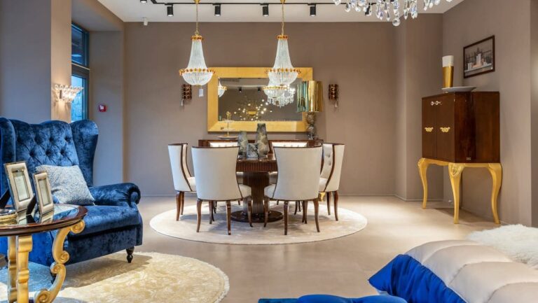 Luxurious dining room with crystal chandeliers, round table with white chairs, blue velvet armchair, and gold accents