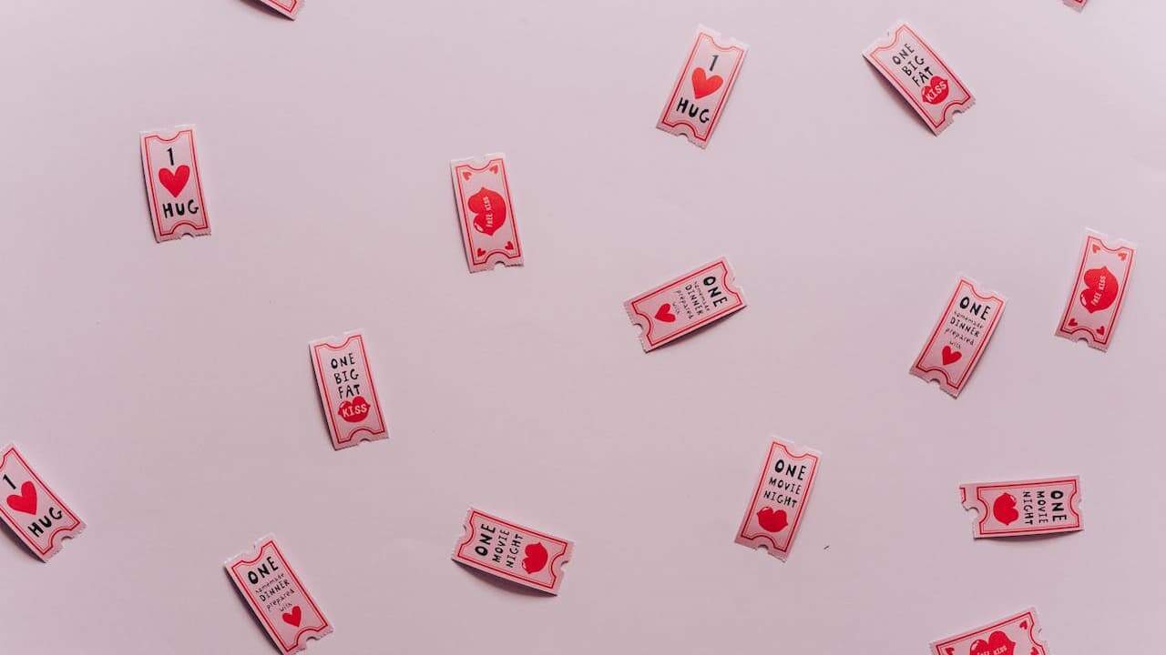 Pink and white Valentine's Day love coupons scattered on light pink background featuring romantic messages and heart symbols