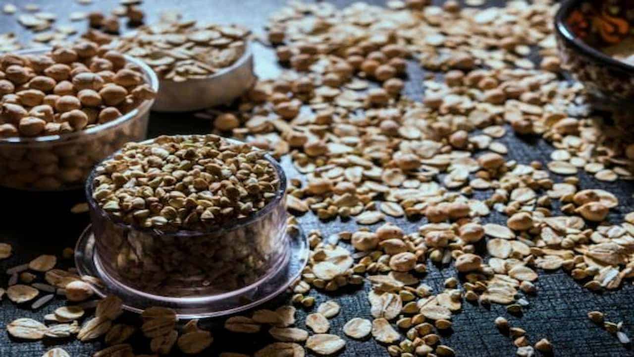 Dry grains scattered on a dark surface with some stored in clear plastic containers
