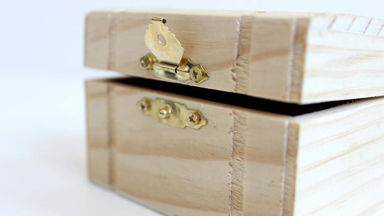 A wooden chest box with visible grain and metal hinges, placed against a plain white background, showcasing a rustic and sturdy design
