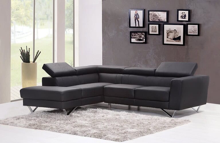 Modern living room with black leather L-shaped sectional sofa, gray area shag rug, framed photos, and tall window with plant