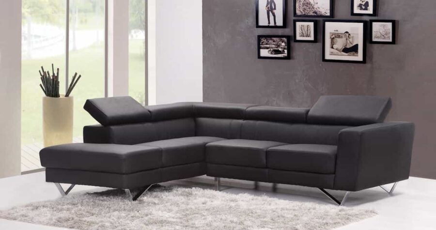 Modern living room with black leather L-shaped sectional sofa, gray area shag rug, framed photos, and tall window with plant