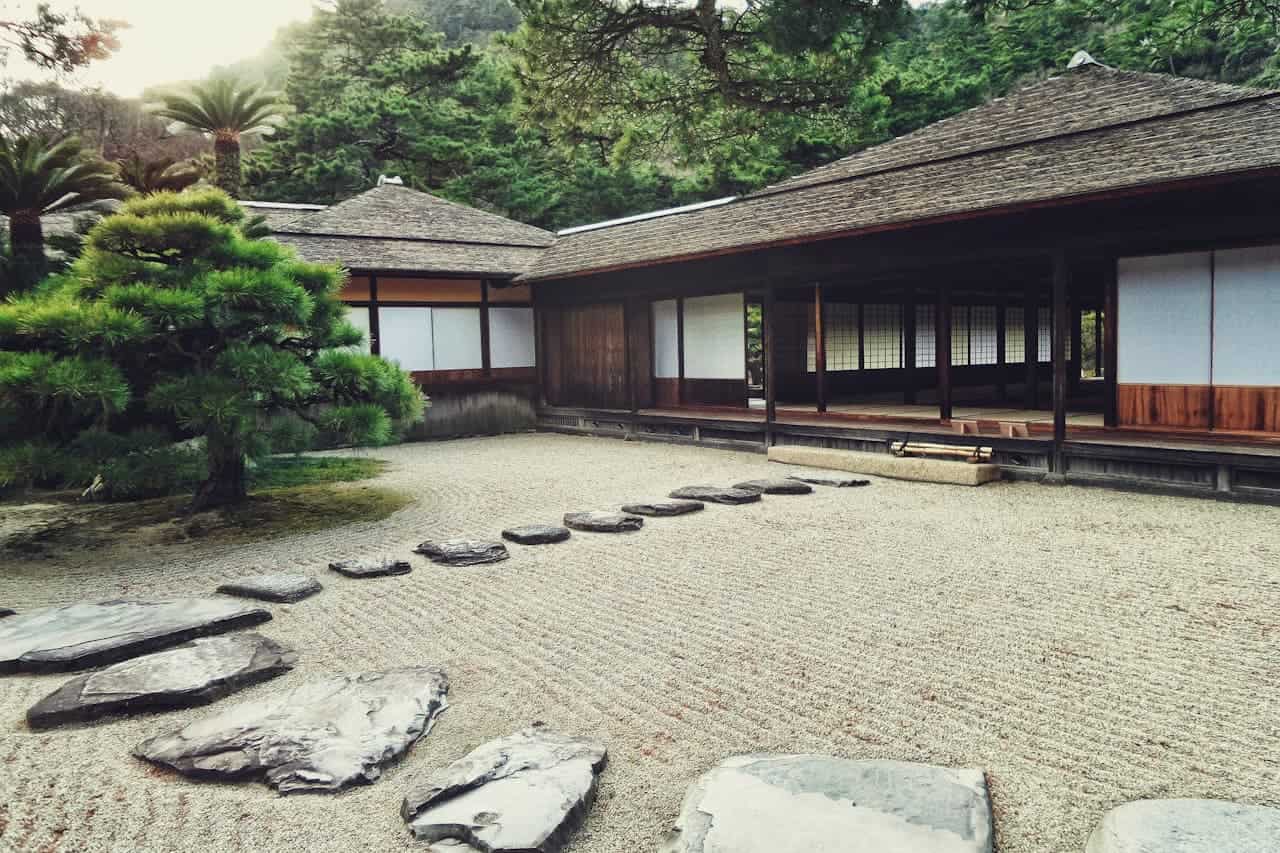 Dwarf Japanese Garden Juniper with raked sand, stepping stones, pine trees, and wooden temple building with verandah and sliding doors