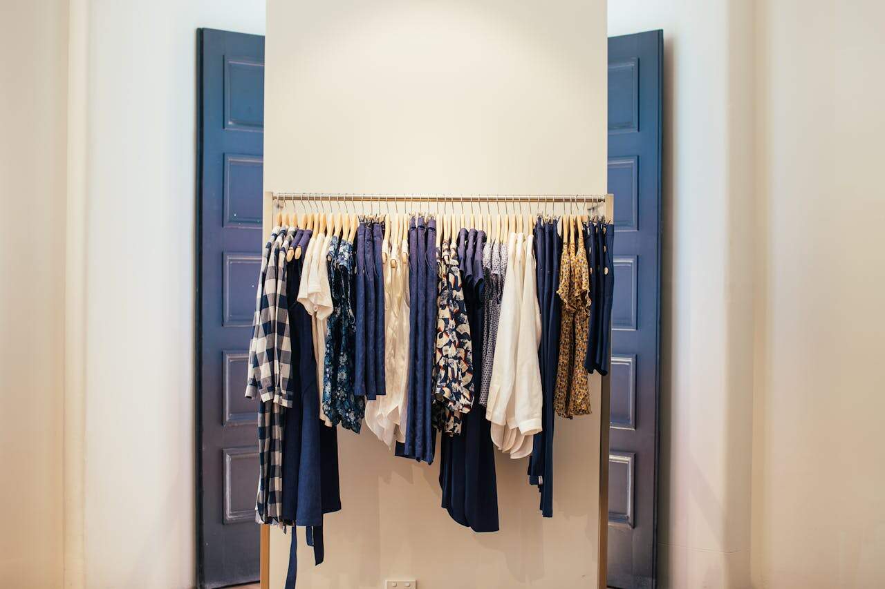 Clothing rack between navy blue doors displaying curated wardrobe with wooden hangers featuring navy, white, and patterned garments