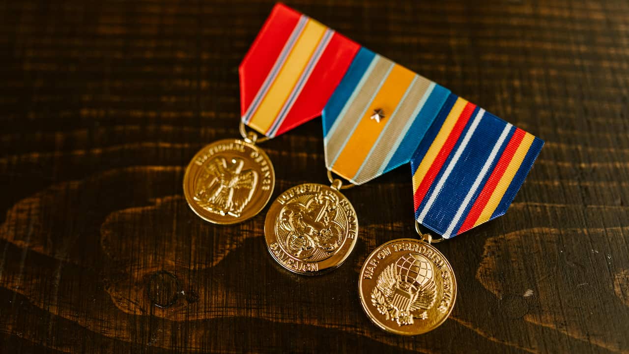A collection of military medals featuring ribbons in blue and red colors, arranged neatly with metal medallions visible, symbolizing honor and service