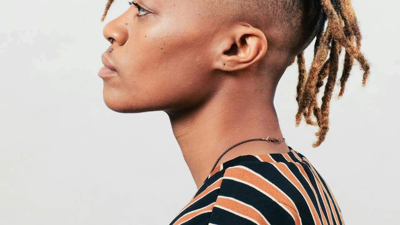 Light brown-skinned person with locs hairstyle, photographed against a plain white background