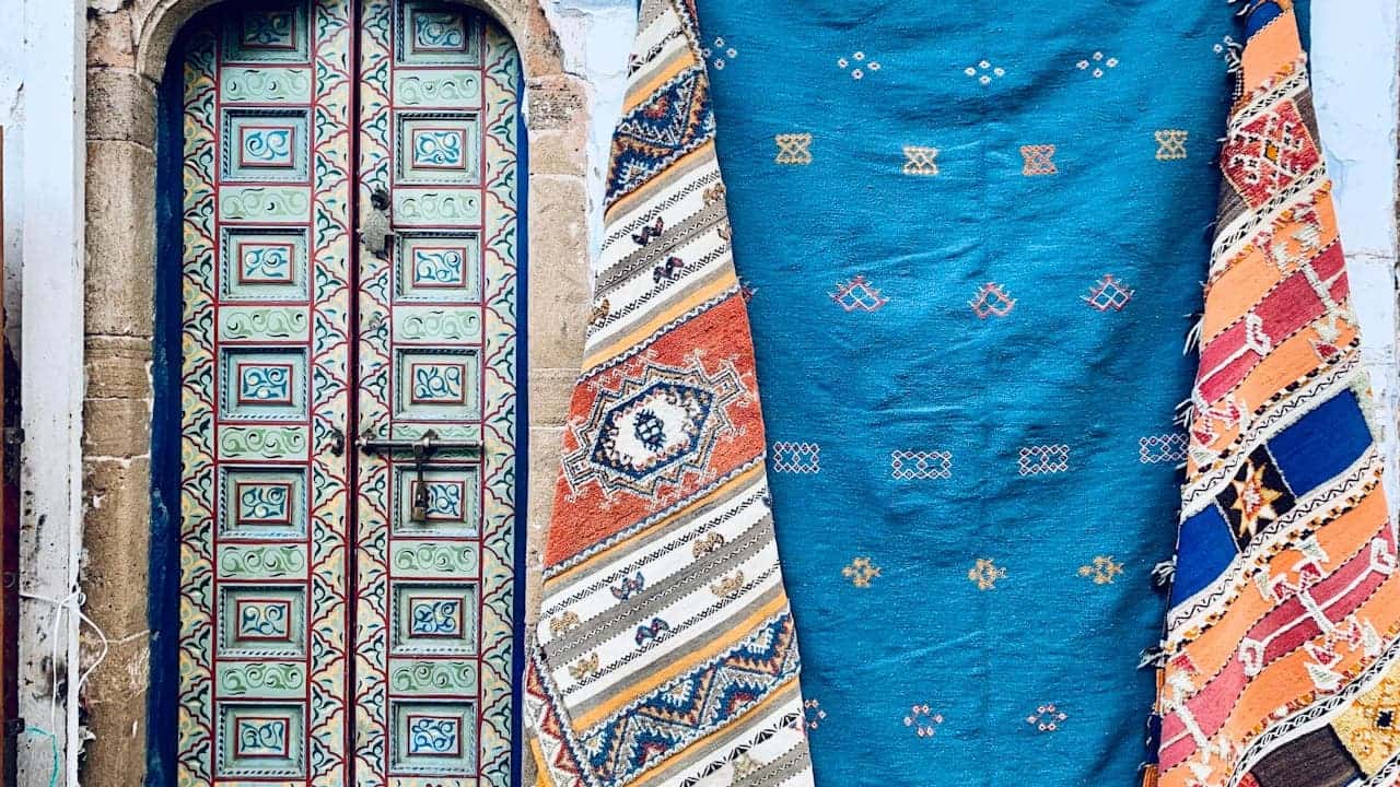 Traditional Peruvian woven textiles hanging as door decoration, featuring bright blue fabric and colorful geometric patterned rugs