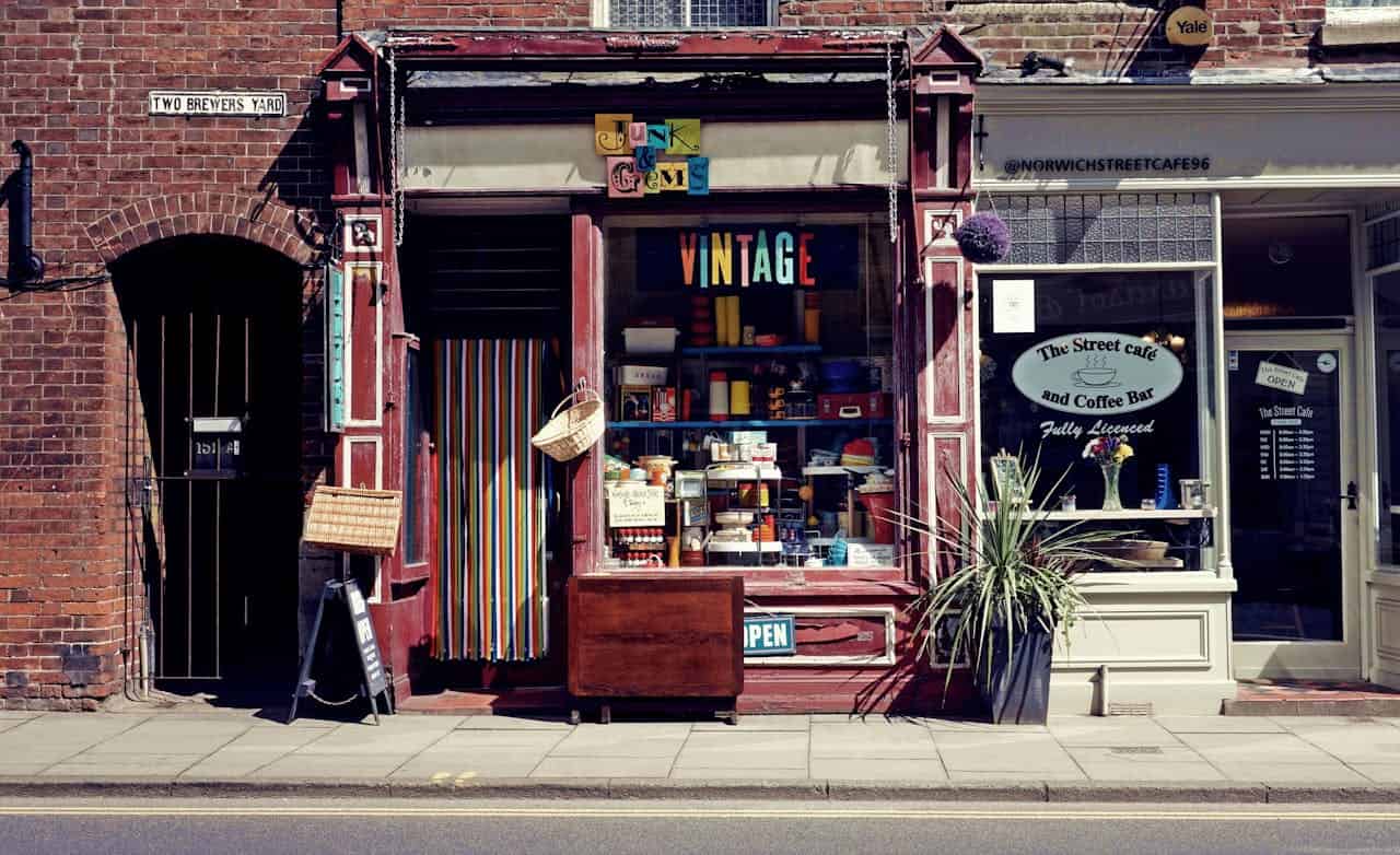 Colorful vintage shop with "Junk and Gems" sign next to "The Street Cafe" in brick building on Two Brewers Yard